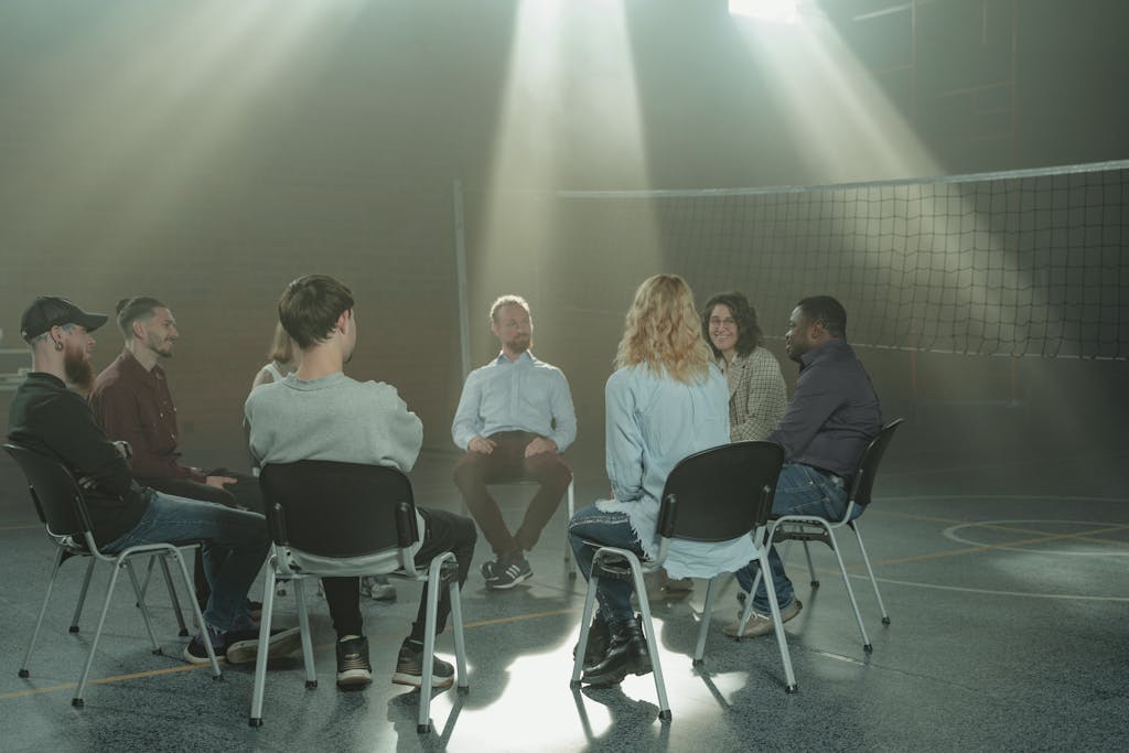 A small group engaging in a therapy session indoors, under rays of sunlight.